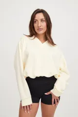 Buzo corto oversize color marfil con elástico en el ruedo inferior y bordado en la espalda.