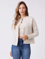 Cardigan tejido de punto color beige, con cuello a la base y cierre frontal mediante un botón metálico decorativo. Presenta mangas largas y corte recto.