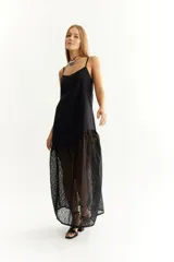 Vestido negro de lino con breteles finos y corte irregular. Presenta una falda larga de encaje floral.