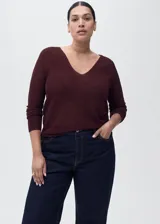 Jersey de punto fino con acabado brillante de lúrex, cuello en pico y manga larga. Presenta un diseño recto y entallado.