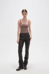 Pantalon de corte flare en color negro, con acabado engomado, tiro medio y cierre frontal con botón y cremallera.