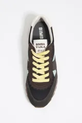 Zapatillas urbanas de la marca Bimba y Lola, confeccionadas en una combinación de serraje vacuno y tejidos técnicos. Presentan un diseño multicolor con base negra y gris, detalles en verde menta y salmón, cordones amarillos y suela dentada de caucho. Incluyen el logotipo de la marca en el estabilizador del talón y la lengüeta.