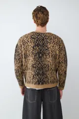 Cardigan de punto con estampado animal print, cuello en V y cierre frontal de botones. Presenta un diseño de textura suave y corte holgado.