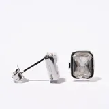 Par de caravanas plateadas con forma rectangular y piedra blanca facetada.