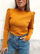 Remera de morley color mostaza, de manga larga con detalle fruncido en los hombros y cuello redondo.