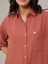 Camisa color beige de algodón y lino, con cuello clásico, cierre frontal con botones, mangas largas con puños abotonados, dos bolsillos con solapa en el pecho y corte holgado.