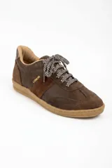 Zapatilla urbana de cuero marrón con detalles en gamuza al tono y aplique metálico con logo de la marca. Cuenta con cordones bicolores y suela de goma color caramelo.