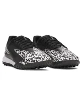 Championes de fútbol Under Armour Shadow Turf 3, diseñados para césped artificial. Presentan un diseño en color negro con detalles gráficos en blanco y negro en la puntera y el talón. Cuentan con suela de goma con tacos estratégicos para un agarre máximo y entresuela Charged Cushioning para mayor amortiguación.