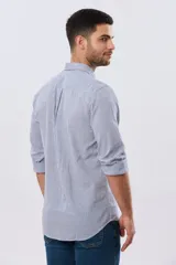 Camisa de lino a cuadros en tonos celeste y blanco, de manga larga, con cuello camisero, cierre frontal con botones y un bolsillo ojal en el pecho con detalle bordado.
