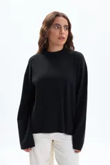 Buzo de tejido de punto color negro, con cuello redondo alto (cuello a la base) y mangas anchas.