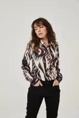 Camisa de manga larga con estampado abstracto en tonos marrones y blancos, cuello camisero y cierre frontal con botones. Puños con detalle de estampado animal print.