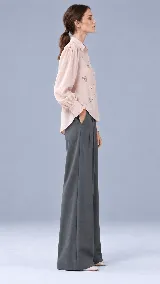 Camisa de color crudo con cuello camisero clásico, mangas abullonadas con puños estructurados terminados en ondas y delicados bordados florales en la parte frontal.