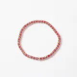 Pulsera elástica compuesta por cuentas de cristal facetado en color rojo intercaladas con pequeñas arandelas metálicas doradas.