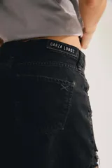 Short de denim negro de tiro alto, con roturas y flecos en el ruedo.