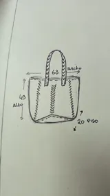 Bolso tipo tote de cuero color marrón, con diseño artesanal que presenta detalles de costuras trenzadas en los laterales y en el centro. Cuenta con dos asas superiores trenzadas y un tamaño amplio.