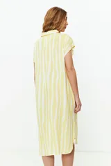 Vestido camisero amarillo con rayas verticales blancas, sin mangas y con botones rojos.