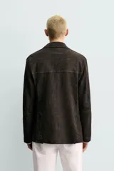 Blazer de corte relajado confeccionada en piel con acabado de ante. Presenta cuello con solapas de muesca, cierre frontal de dos botones, mangas largas y bolsillos de plastrón en la cadera. El diseño no posee forro interior y cuenta con aberturas en la parte trasera.