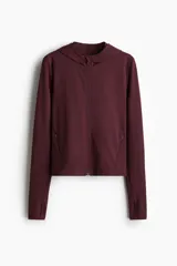 Campera deportiva de corte ajustado con capucha, cierre frontal completo y bolsillos laterales con cierre. Confeccionada en tejido funcional con tecnología de absorción de sudor, presenta mangas largas con aberturas para los pulgares.