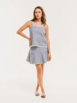 Falda corta color beige con rayas verticales blancas, corte evasé y volado en el ruedo.