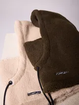 Pasamontañas de tejido tipo corderito sintético en color negro, con diseño de capucha integrada y cordones ajustables en la parte frontal.