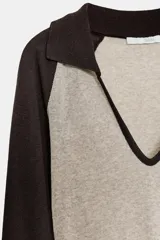 Camiseta de manga larga, corte slim fit, con cuerpo color beige claro y mangas y cuello polo en color marrón oscuro. Presenta un escote en pico bajo el cuello polo.