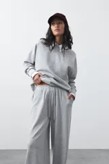 Pantalón de corte holgado y pierna ancha, con cintura elástica ajustable mediante cordón. Presenta bolsillos laterales y costuras verticales decorativas que recorren el frente de las piernas.