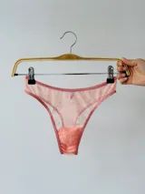 Pantie tipo tanga de microtul color salmón con estampado de pequeñas flores y bordes en color rosa.