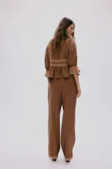 Pantalón de pierna recta color marrón con leve brillo, cintura elástica con cordón ajustable y ribetes de encaje en los bajos.
