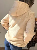 Campera con cuerpo de piel sintética tipo teddy y mangas acolchadas. Presenta cierre frontal, capucha y diseño de corte recto.