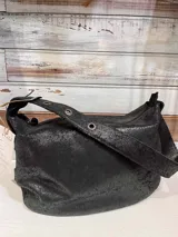 Bolso de hombro tipo hobo con acabado texturizado efecto craquelado en tonos beige y blanco. Cuenta con una correa ajustable con hebilla metálica, cierre superior y diseño espacioso.