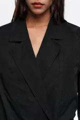 Chaquetón sastrero negro de doble botonadura en mezcla de algodón y poliamida, con solapas de muesca, mangas largas, bolsillos frontales de parche y pespuntes decorativos.