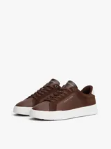Zapatillas de corte bajo Tommy Hilfiger confeccionadas en una combinación de piel nobuk y piel lisa en color marrón. Presentan suela de goma blanca, detalle de ventilación lateral, logo de la marca en la lengüeta, lateral y talón, y cierre mediante cordones.
