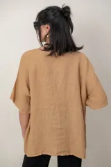 Blusa de lino color blanco, de corte amplio, con escote redondo, mangas cortas y detalle de guarda calada horizontal en la parte inferior.