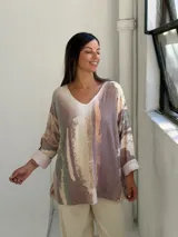 Sweater de punto con diseño abstracto en tonos tierra, verde y beige, de corte holgado, cuello en V y mangas largas con puños vueltos.