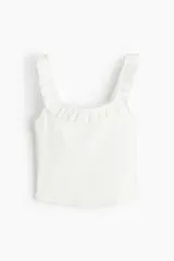 Musculosa de punto acanalado de algodón, color blanco, con escote cuadrado y breteles anchos decorados con volados fruncidos.