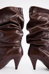 Bota de caña media en cuero negro con diseño slouchy, punta fina y taco cónico de altura media.