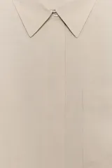 Camisa de corte fluido confeccionada en mezcla de modal, con cuello solapa, manga corta y bolsillo de plastrón en el delantero. Presenta cierre frontal con botones ocultos por tapeta y bajo con aberturas laterales.