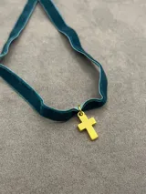 Gargantilla tipo choker confeccionada en cinta de terciopelo color verde petróleo, con dije de cruz en acabado dorado.