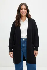 Sacón largo de punto abierto, color negro, con diseño oversize, mangas largas con puños ajustados y bolsillos laterales frontales.