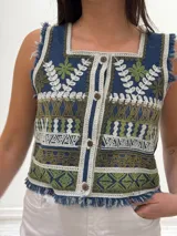 Chaleco corto en denim con bordado artesanal multicolor y escote cuadrado. Con cierre de botones y terminaciones desflecadas.