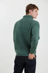 Sweater verde de punto inglés con cuello alto y cierre metálico frontal. Tiene mangas largas y terminaciones en punto canalé.