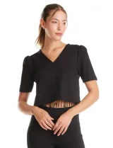 Blusa negra de corte corto con escote en V, mangas cortas con sutil efecto abullonado en los hombros y ruedo decorado con flecos de cuentas negras.