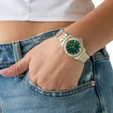 Reloj analógico Guess modelo Colette con caja de 32 mm, esfera de nácar verde y bisel decorado con cristales. Presenta una correa de acero inoxidable en tono bicolor dorado y plateado.