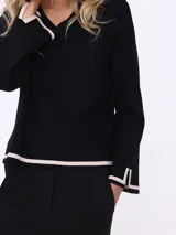 Sweater negro de escote en V con terminación de contorno marcado en color crudo.
