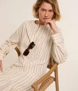 Vestido chemise midi de corte camisero, con escote en pico y botonadura frontal parcial. Presenta mangas 3/4 y un diseño de rayas verticales en tonos claros.