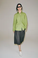 Camisa oversize de popelín de algodón color verde claro, con cuello solapa y manga larga. Cierre frontal con botones ocultos y bajo redondeado.