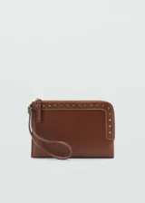 Funda de poliuretano efecto piel color marrón, con detalle de tachuelas metálicas doradas, cierre de cremallera y asa corta de mano.