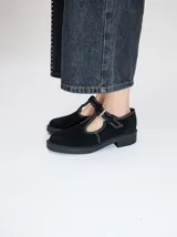 Zapatos tipo guillermina de gamuza color bordó, con diseño de tira en T, cierre con hebilla metálica y costuras a la vista en hilo blanco. Poseen una suela de plataforma de goma negra de 4 cm.