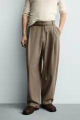 Pantalón de corte balloon fit en color gris, confeccionado en tejido con viscosa. Presenta pliegues frontales, cintura con cinturón integrado a contraste, bolsillos laterales y bolsillos traseros de vivo.