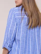 Camisa de lino de la marca Dash, color beige con rayas verticales blancas. Cuenta con cuello camisero, cierre frontal con botones, un bolsillo aplicado en el pecho y mangas largas con sistema de ajuste para arremangar.